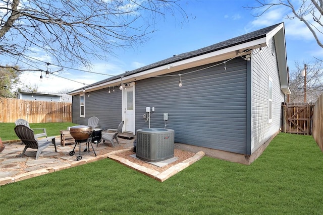 rear view of property with a fenced backyard, an outdoor fire pit, cooling unit, a yard, and a patio area