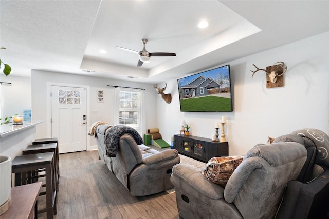 living area featuring wood finished floors, visible vents, recessed lighting, ceiling fan, and a raised ceiling