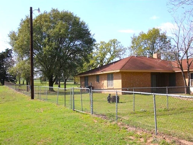 view of side of property featuring brick siding, a lawn, a chimney, and fence