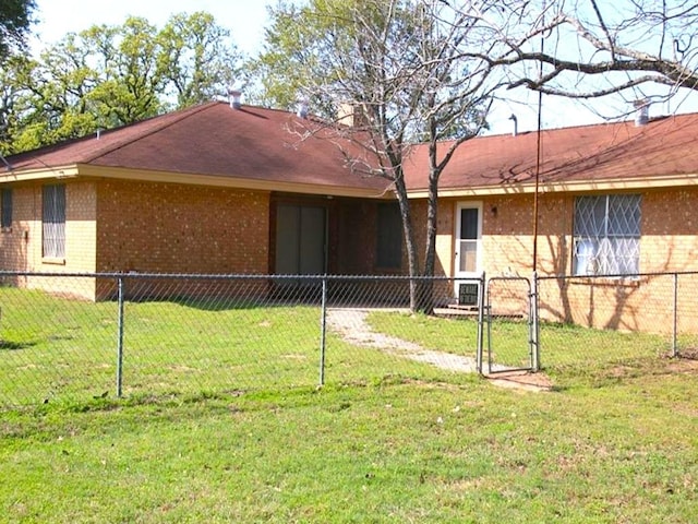 rear view of property with brick siding, a lawn, a gate, and fence