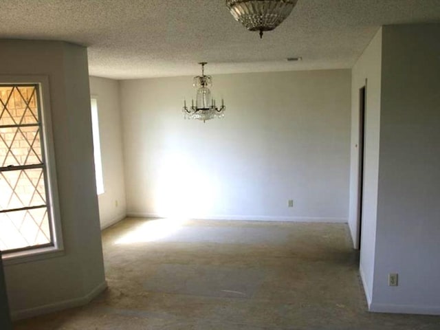 unfurnished dining area with baseboards, a notable chandelier, carpet floors, and a textured ceiling