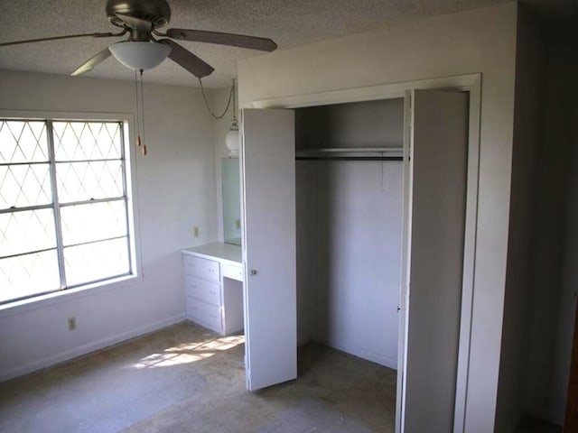 unfurnished bedroom with concrete floors, baseboards, a closet, a textured ceiling, and a ceiling fan