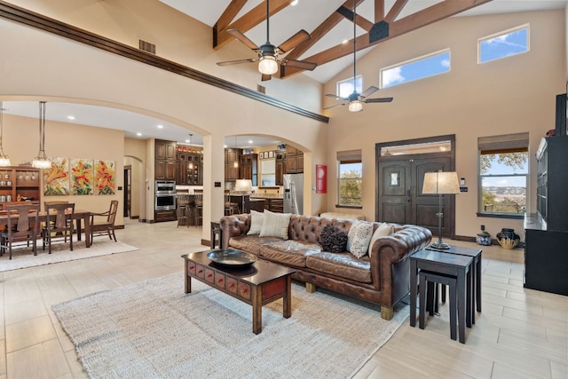 living room featuring beamed ceiling, visible vents, arched walkways, and a healthy amount of sunlight