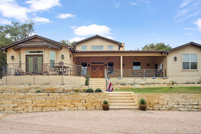 view of front of home with french doors, a porch, and stucco siding