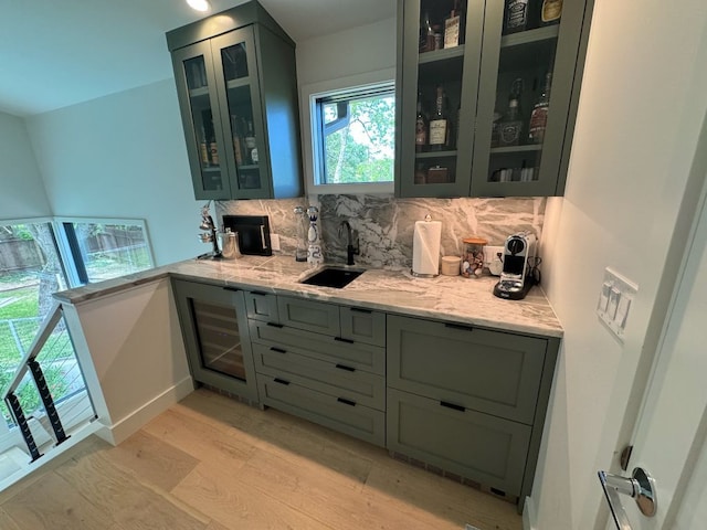 bar featuring indoor wet bar, decorative backsplash, light wood-type flooring, and a sink