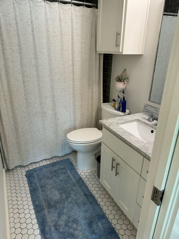 full bathroom with toilet, vanity, and tile patterned flooring