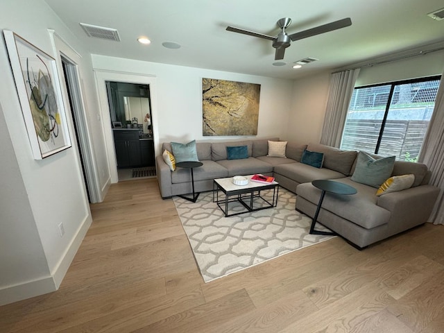 living area featuring baseboards, light wood-style floors, visible vents, and ceiling fan