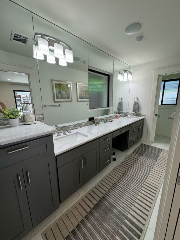 full bathroom with a sink, visible vents, double vanity, and tile patterned floors