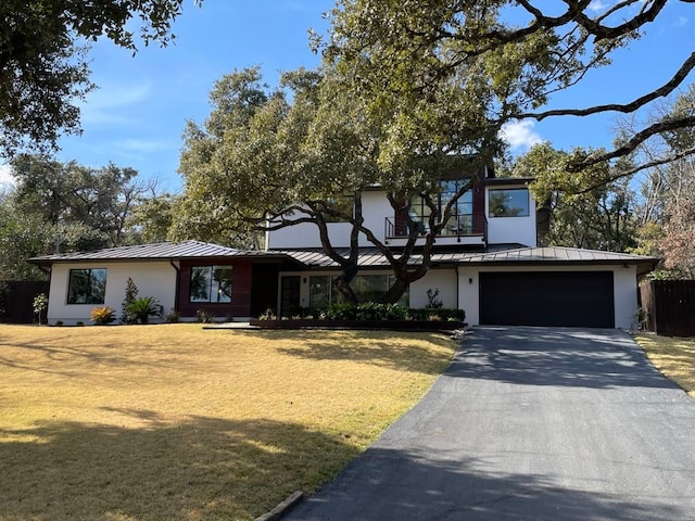 view of front of property with driveway, a standing seam roof, stucco siding, a front lawn, and metal roof