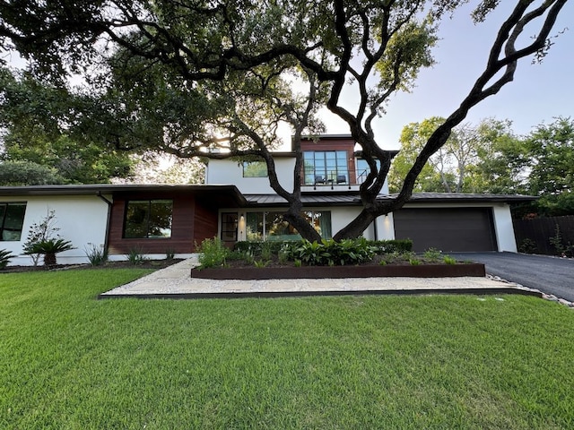 view of front of home featuring a front lawn, an attached garage, aphalt driveway, and stucco siding