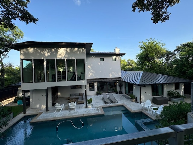 rear view of house with a patio, metal roof, a standing seam roof, a chimney, and an outdoor hangout area