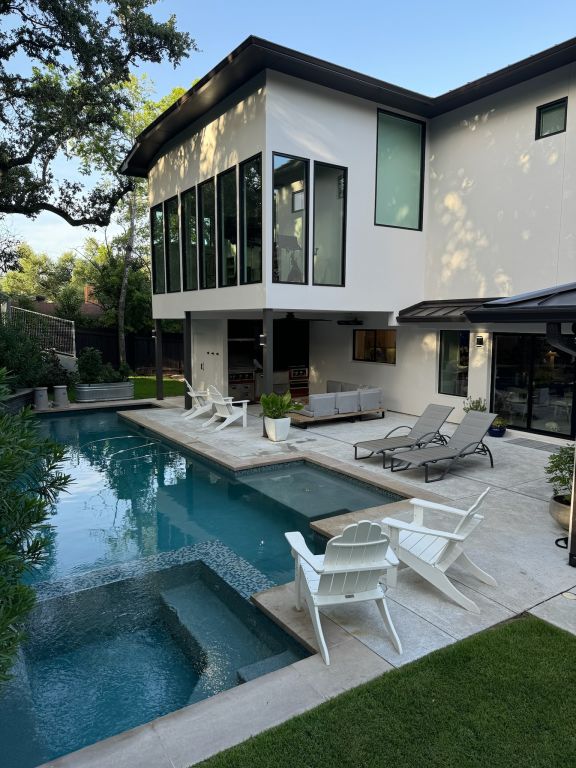 212 Westhaven Dr, West Lake Hills, TX 78746 - back of property featuring stucco siding, a patio area, a pool with connected hot tub, and an outdoor hangout area