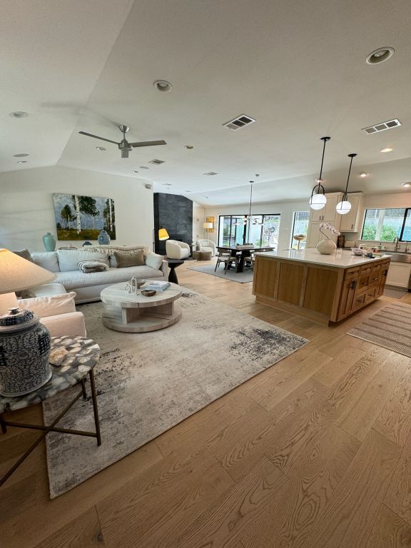 living room with light wood-type flooring, visible vents, a ceiling fan, and recessed lighting