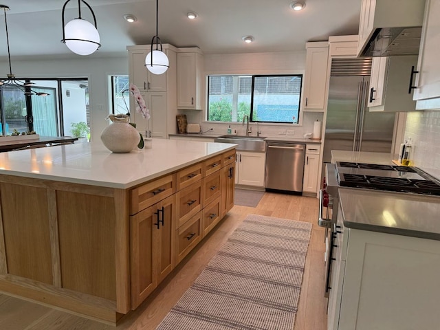 kitchen with tasteful backsplash, under cabinet range hood, premium appliances, white cabinets, and a sink