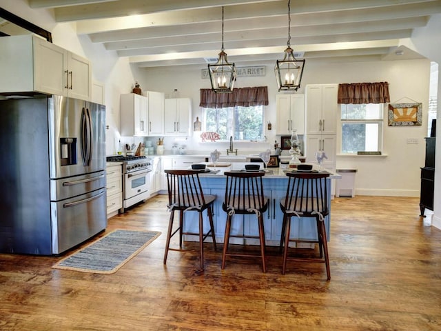 kitchen featuring a breakfast bar, wood finished floors, a center island, white cabinetry, and appliances with stainless steel finishes