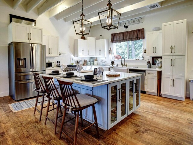 kitchen with a breakfast bar area, visible vents, stainless steel appliances, light countertops, and white cabinets
