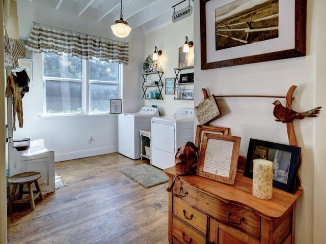 laundry room with washer and dryer, baseboards, and wood finished floors
