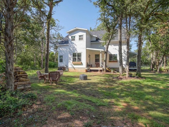 rear view of house with a fire pit and a lawn