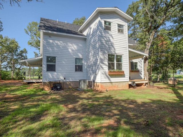 rear view of property featuring central air condition unit and a lawn
