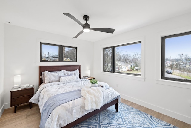 bedroom with a ceiling fan, baseboards, and light wood-type flooring