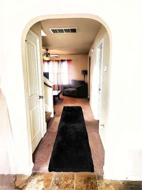 hallway with visible vents, arched walkways, carpet, and stairway