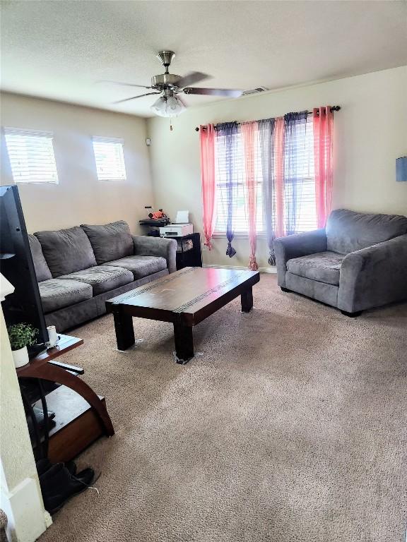 living area with visible vents, ceiling fan, and carpet floors