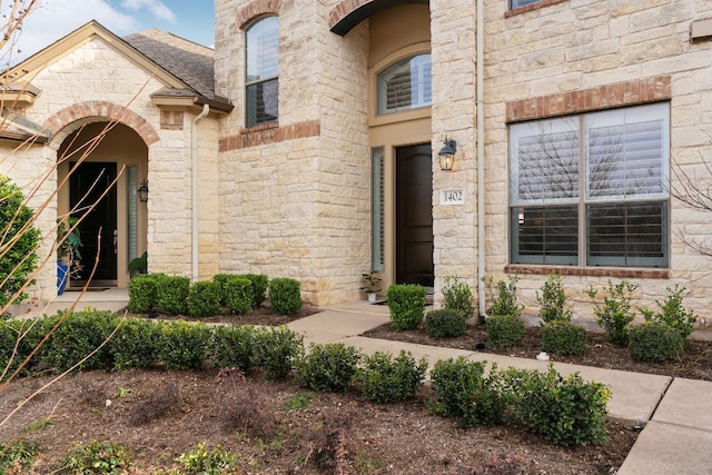 entrance to property featuring roof with shingles