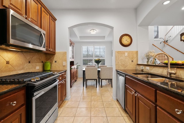 14100 Avery Ranch Blvd Unit 1402, Austin, TX 78717 - kitchen featuring stainless steel appliances, a sink, arched walkways, dark stone counters, and decorative backsplash