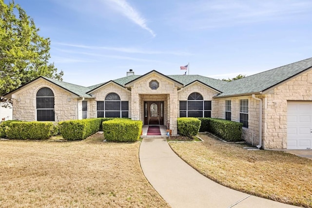20531 Highland Lake Dr, Lago Vista, TX 78645 - french country style house featuring stone siding, a chimney, roof with shingles, a front lawn, and an attached garage