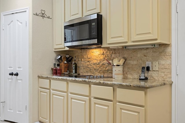 20531 Highland Lake Dr, Lago Vista, TX 78645 - kitchen with stainless steel microwave, tasteful backsplash, black electric cooktop, and light stone countertops
