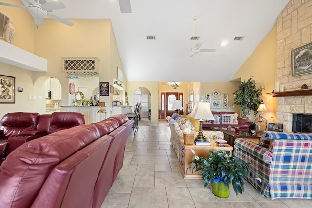 20531 Highland Lake Dr, Lago Vista, TX 78645 - living area with ceiling fan, high vaulted ceiling, arched walkways, a stone fireplace, and light tile patterned floors