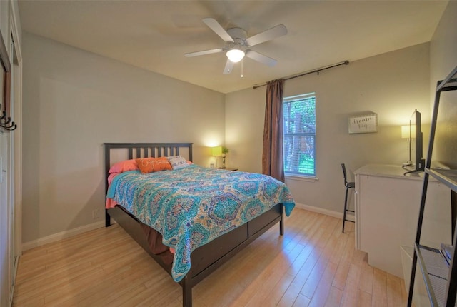 bedroom with light wood-type flooring, baseboards, and a ceiling fan