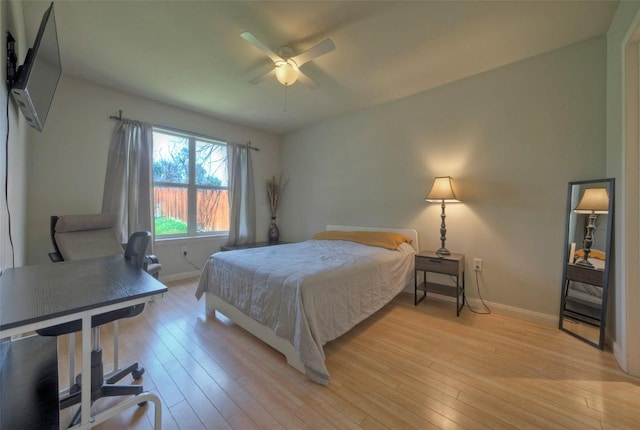 bedroom with light wood-style floors, baseboards, and ceiling fan