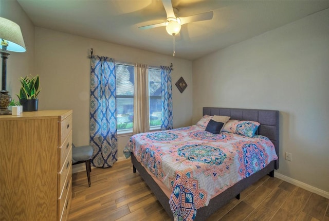 bedroom with a ceiling fan, wood finished floors, and baseboards