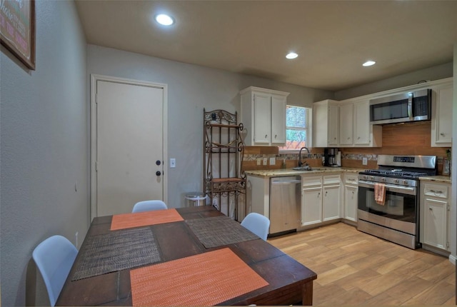 kitchen with light wood-style flooring, stainless steel appliances, light countertops, and a sink