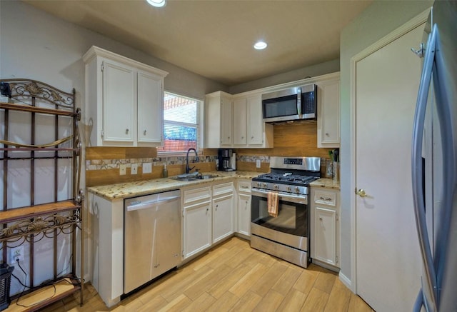 kitchen with decorative backsplash, white cabinets, appliances with stainless steel finishes, and a sink