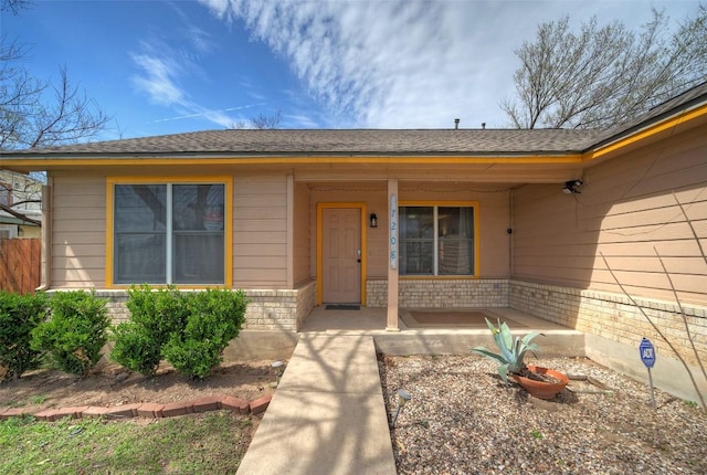 view of exterior entry featuring brick siding and covered porch