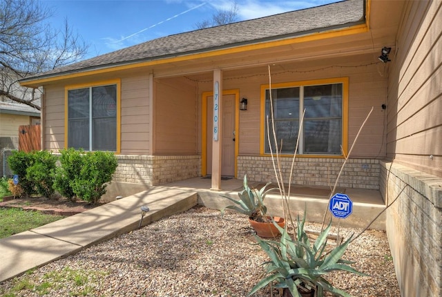 doorway to property featuring brick siding and a porch