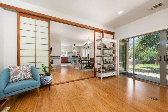 interior space featuring a wealth of natural light, visible vents, wood finished floors, and a chandelier