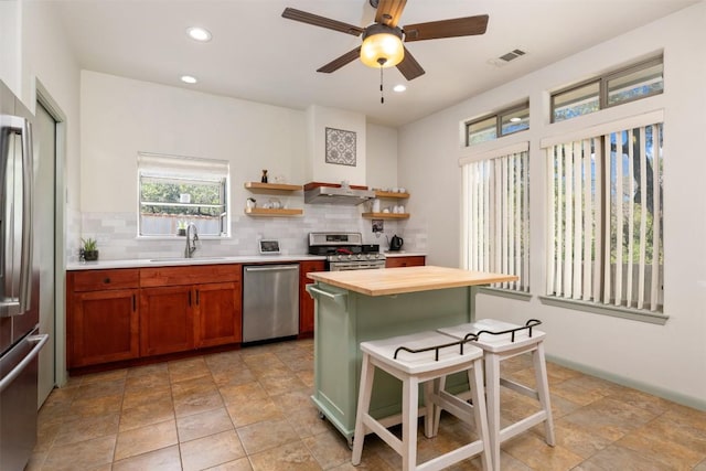 kitchen featuring visible vents, wooden counters, under cabinet range hood, appliances with stainless steel finishes, and a sink