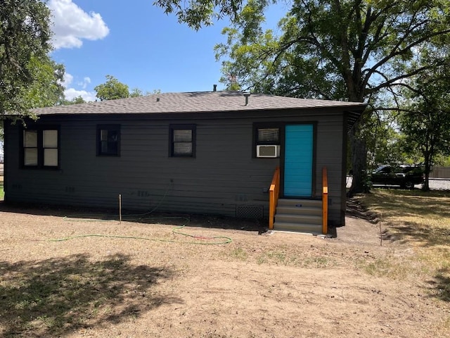 exterior space with cooling unit and a shingled roof