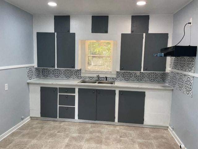 kitchen with backsplash, light countertops, baseboards, and a sink