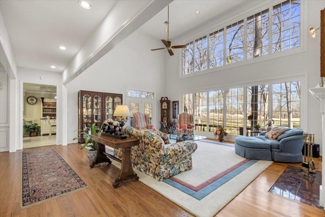 living room with recessed lighting, wood finished floors, a towering ceiling, and ceiling fan