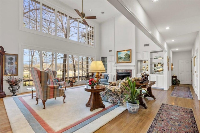 living area featuring visible vents, recessed lighting, a fireplace, wood finished floors, and a ceiling fan