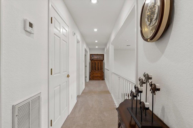 corridor with recessed lighting, visible vents, light carpet, and a textured wall