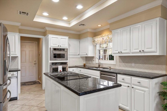 kitchen with visible vents, appliances with stainless steel finishes, a tray ceiling, and a sink