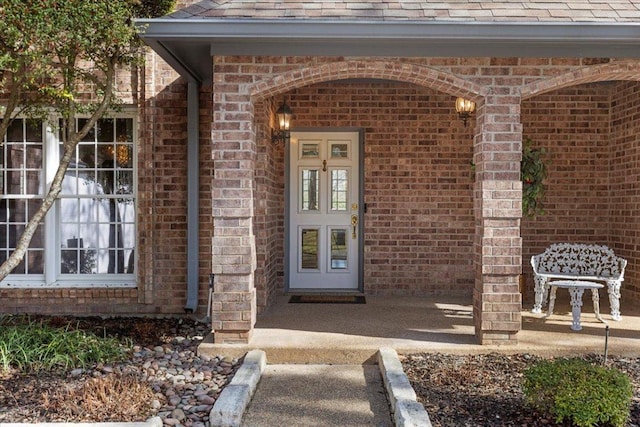 property entrance with brick siding and a shingled roof