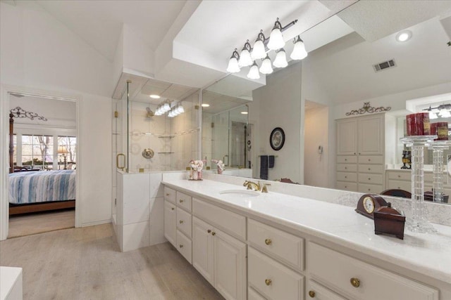 ensuite bathroom featuring visible vents, connected bathroom, lofted ceiling, a stall shower, and wood finished floors