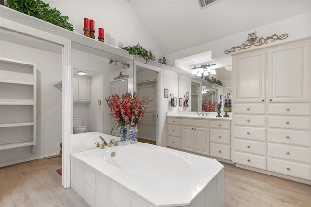 bathroom featuring toilet, vanity, lofted ceiling, and wood finished floors