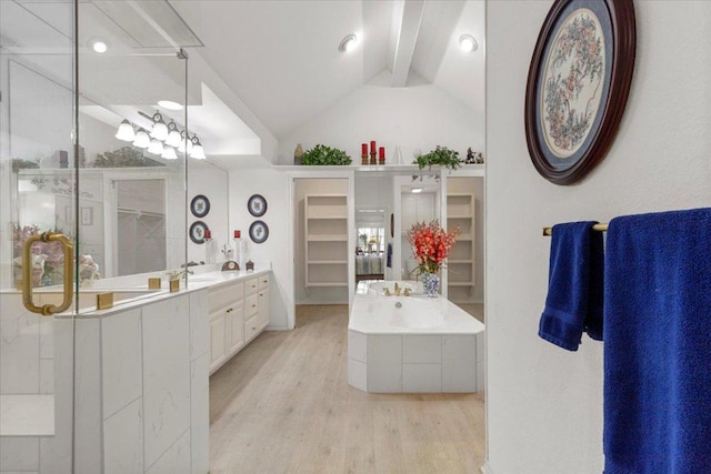 bathroom featuring vanity, wood finished floors, lofted ceiling with beams, a walk in closet, and a garden tub